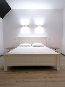 a white bed in a white room with lights on it at Pensiunea Edelweiss in Voineasa