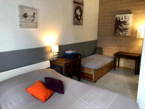 アル・アン・レにあるLes Nuits Bleuesのベッド2台、テーブル、ベッド1台が備わる客室です。
