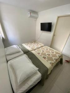 1 dormitorio con 1 cama con manta y TV en F&F INN a 50 mts da Praia de Ponta Verde, en Maceió