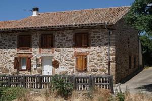Casa Rural Alto Santiago في Santiago del Collado: منزل حجري امامه سور خشبي