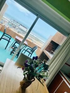 un jarrón de flores sobre una mesa con vistas a la playa en Departamentos Sobre el Mar en Villa Gesell