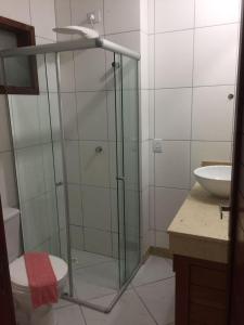 a bathroom with a glass shower with a toilet and a sink at Condomínio Brisas do Amor in Pipa