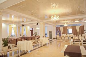 a banquet hall with white tables and chairs and chandeliers at Готель Баронський Двір in Chernivtsi