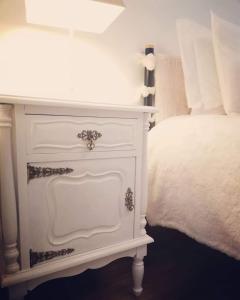 a white nightstand next to a white bed at Alojamento Local Ferros - Duplex in Viana do Castelo