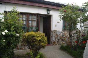 una casa blanca con una puerta y algunas plantas en Casa Elena en Ushuaia
