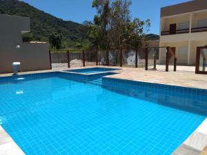 a large blue swimming pool in front of a building at Chalés São Mateus in Ubatuba