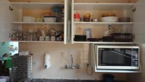 eine Küche mit einer Mikrowelle und etwas Geschirr auf Regalen in der Unterkunft Casa 200m da praia 3 dorm. p/ 12 pessoas in Peruíbe