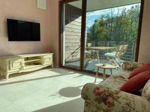 a living room with a couch and a television and a balcony at VILLA COLLINA VERDE in Bolzano