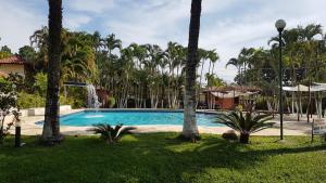 a swimming pool with palm trees and a fountain at Flat 47 SUN HOUSE Maresias in Maresias