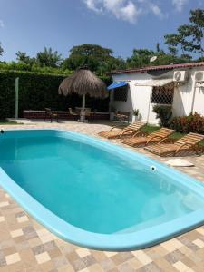 une grande piscine bleue avec des chaises et une maison dans l'établissement Cabaña Coveñas, à Coveñas