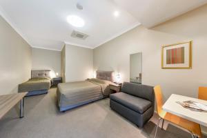 una camera d'albergo con due letti e una sedia di Cessnock Motel a Cessnock