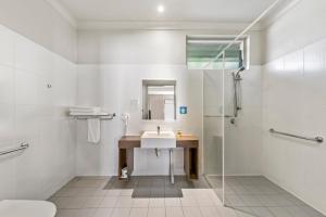 ein weißes Bad mit einem Waschbecken und einer Dusche in der Unterkunft Cessnock Motel in Cessnock