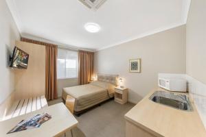 a small hotel room with a bed and a sink at Cessnock Motel in Cessnock