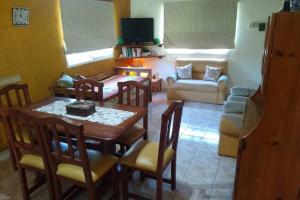 sala de estar con mesa, sillas y sofá en Cabaña Villa Allende en Villa Allende