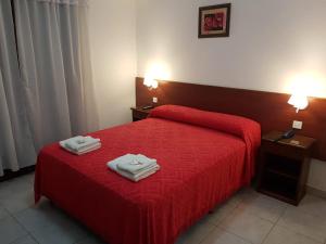 a bedroom with a red bed with two towels on it at Hotel Nadai in Mar del Plata