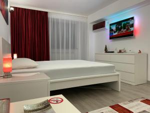 a bedroom with a white bed and a tv on the wall at Mery Apartment in Galaţi