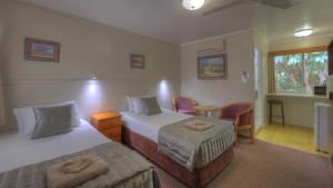 a hotel room with two beds and a table and chairs at Atherton Hinterland Motel in Atherton
