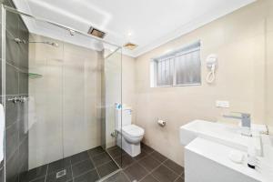a bathroom with a shower and a toilet and a sink at WM Bankstown in Bankstown