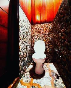 a bathroom with a toilet with a stone wall at Aldejus Homestay in Yennanas Besir