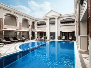 una piscina de hotel con sillas y sombrillas en The Langham Hong Kong, en Hong Kong