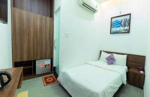 um pequeno quarto com uma cama e uma televisão em Hoa Cát Hotel em Quy Nhon