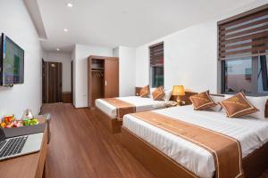 una habitación de hotel con 2 camas y un ordenador portátil en un escritorio en Victoria Hotel Ninh Binh, en Ninh Binh
