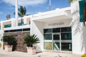 eine Fassade eines weißen Gebäudes mit Palmen davor in der Unterkunft Hotel Maioris Navolato in San Pedro