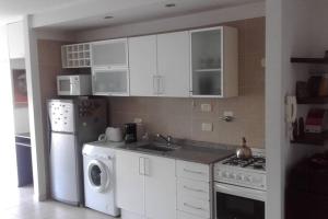 a kitchen with white cabinets and a washer and dryer at Departamento confortable en Congreso in Buenos Aires