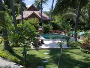 a resort yard with a swimming pool and palm trees at Villa Selina in Tejakula