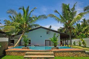 a villa with a swimming pool and palm trees at Villa Tangalle Lagoon in Tangalle