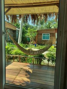 a hammock on a deck with a house at Mook Montra Resort Sea Front in Koh Mook
