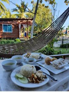 a table with plates of food on a hammock at Mook Montra Resort Sea Front in Koh Mook
