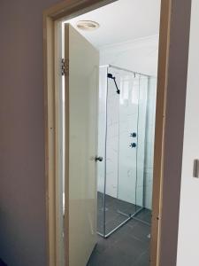 a glass shower door in a bathroom with at Branxton House Motel in Branxton