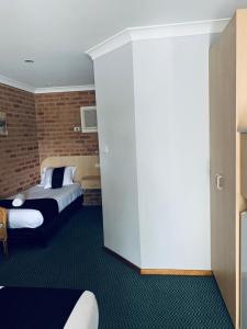 a bedroom with two beds and a brick wall at Branxton House Motel in Branxton