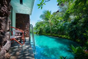 a pool in a house with a chair next to it at MERUSAKA Nusa Dua in Nusa Dua
