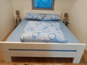 a bed with blue and white sheets and pillows at FLAMANITA APARTMENTS in Skopje