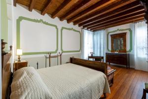 a bedroom with a bed and two large windows at Palazzo Scolari in Polcenigo