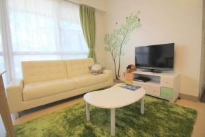 ein Wohnzimmer mit Sofa und Fernseher in der Unterkunft 沖縄ライフインゼファー Okinawa Totoro House in Tōbaru