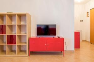Czerwona szafka z telewizorem na górze w obiekcie GoodStay Archimede Apartment w mieście Lecce
