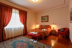 una camera da letto con un letto, due sedie e una finestra di Hotel Rutiliano a Pienza