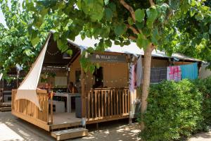a wooden building with a table and a tree at Glamping Blanes in Blanes