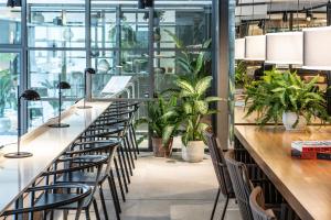 a row of tables and chairs in a room with plants at INNSiDE by Meliá Zaragoza in Zaragoza