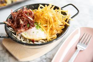 a black plate of food with spaghetti and cheese at INNSiDE by Meliá Zaragoza in Zaragoza