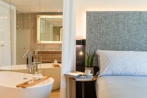 a bedroom with a bed and a tub and a sink at INNSiDE by Meliá Zaragoza in Zaragoza
