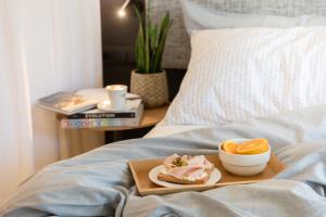 a plate with a sandwich and a bowl of oranges on a bed at INNSiDE by Meliá Zaragoza in Zaragoza