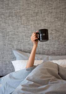 a person holding a cup in their hand on a bed at INNSiDE by Meliá Zaragoza in Zaragoza
