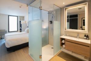 a bathroom with a bed and a shower and a sink at INNSiDE by Meliá Zaragoza in Zaragoza