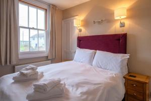a bedroom with a white bed with towels on it at 4 Old Homes, Thorpeness - Only a stones throw from the beach - Aldeburgh Coastal Cottages in Thorpeness