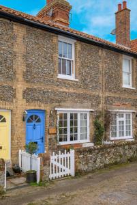 a brick house with blue doors and a white fence at 4 Old Homes, Thorpeness - Only a stones throw from the beach - Aldeburgh Coastal Cottages in Thorpeness