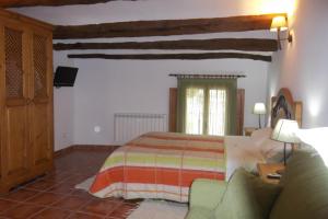 1 dormitorio con 1 cama y 1 sofá en Casa Rural La Buhardilla, en Las Cuevas de Cañart